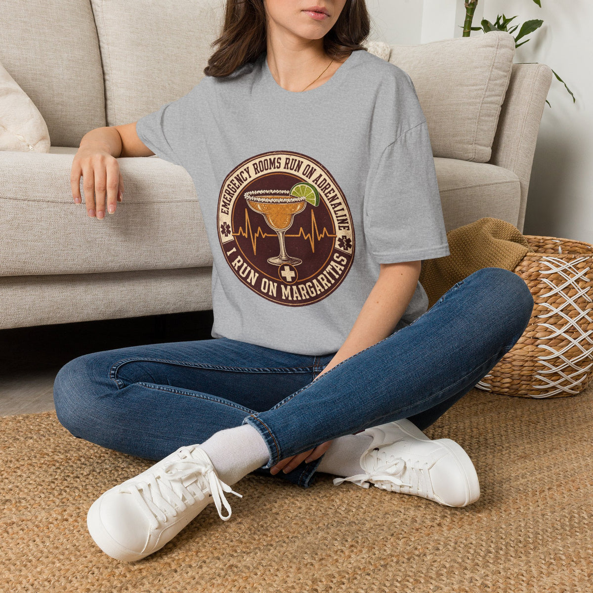 Emergency Rooms Run on Adrenaline Shirt, Sport Grey, worn by a model seated on the floor beside a sofa