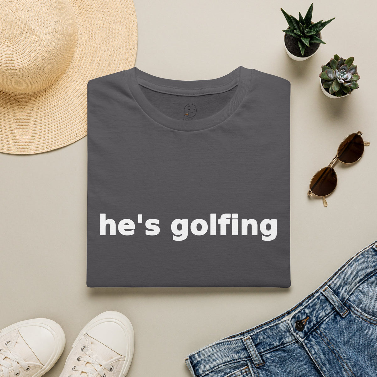 Golf Widow Shirt, Charcoal grey, folded flat lay styled with a straw hat, sunglasses, sneakers and denim