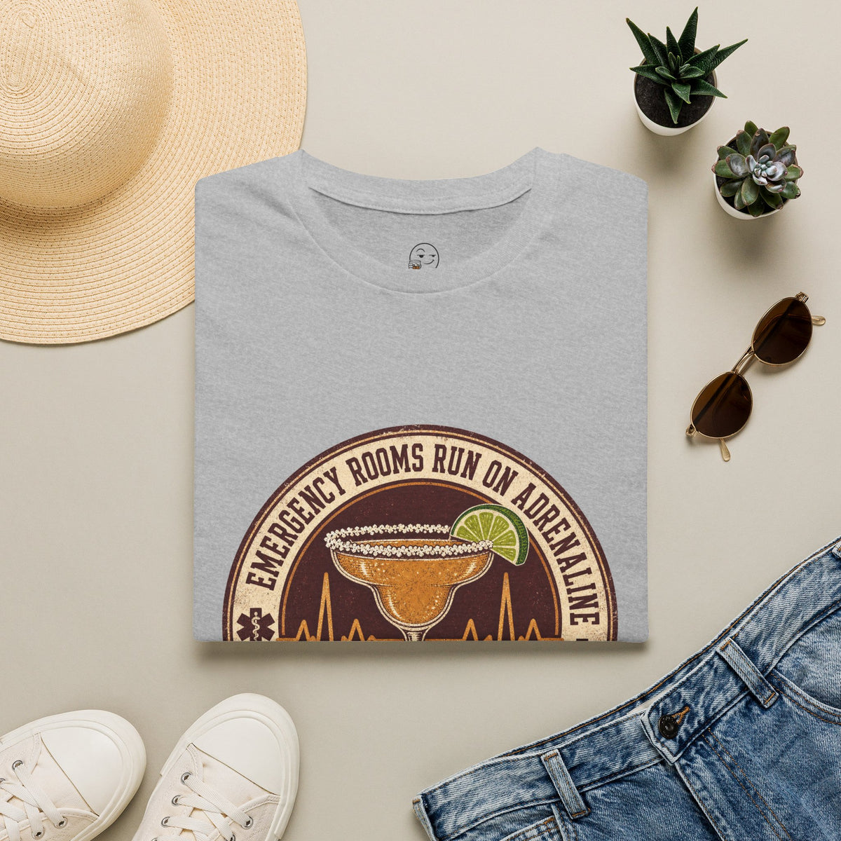 Emergency Rooms Run on Adrenaline Shirt, Sport Grey, folded flat lay styled with a straw hat, sunglasses, sneakers and denim