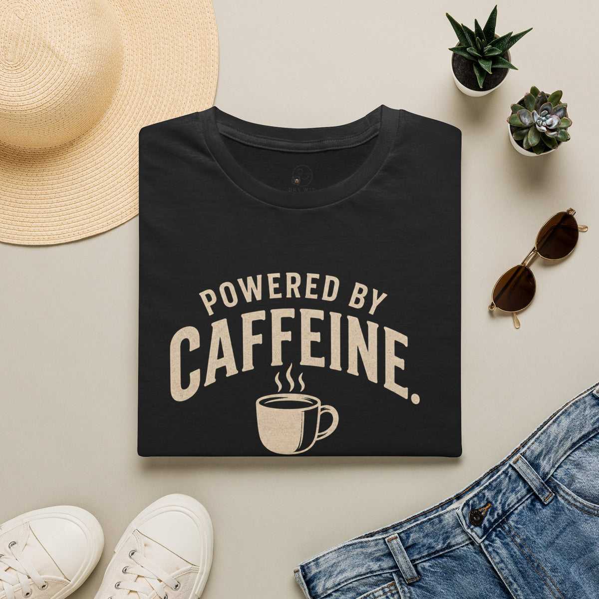 Powered by Caffeine Sponsored by Bourbon Shirt, Black, folded flat lay styled with a straw hat, sunglasses, sneakers and denim