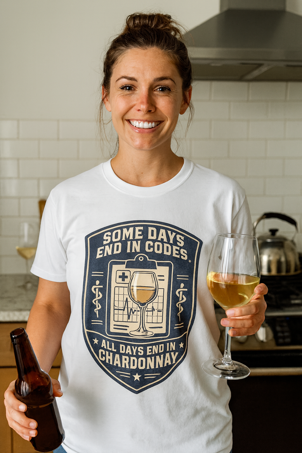 Smiling woman in a white Some Days End in Codes funny ER nurse shirt holding wine and a beer in a kitchen