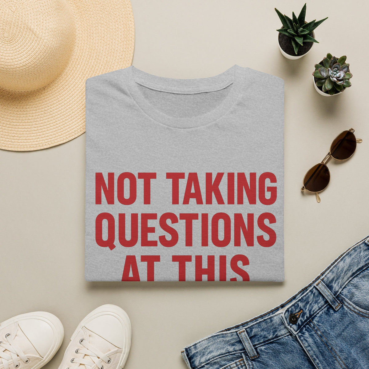 Not Taking Questions at This Time Shirt, Sport Grey, folded flat lay styled with a straw hat, sunglasses, sneakers and denim