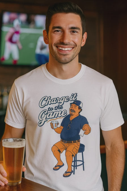 Video of a man in a white Charge It To The Game funny dad drinking shirt in a bar with football on TV behind him