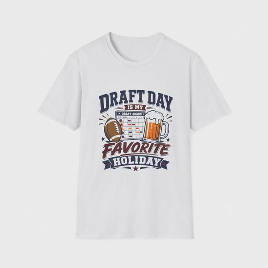 Video of a man standing in his kitchen celebrating with a raised beer while looking at a fantasy football draft board on his phone, wearing a white t-shirt with navy and maroon text reading Draft Day Is My Favorite Holiday, featuring a football, beer mug, and draft board graphic