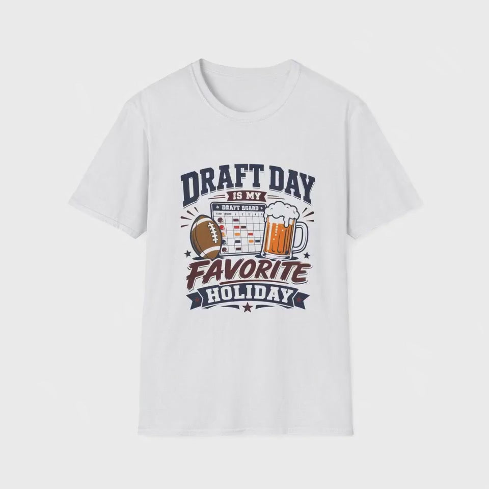 Video of a man standing in his kitchen celebrating with a raised beer while looking at a fantasy football draft board on his phone, wearing a white t-shirt with navy and maroon text reading Draft Day Is My Favorite Holiday, featuring a football, beer mug, and draft board graphic